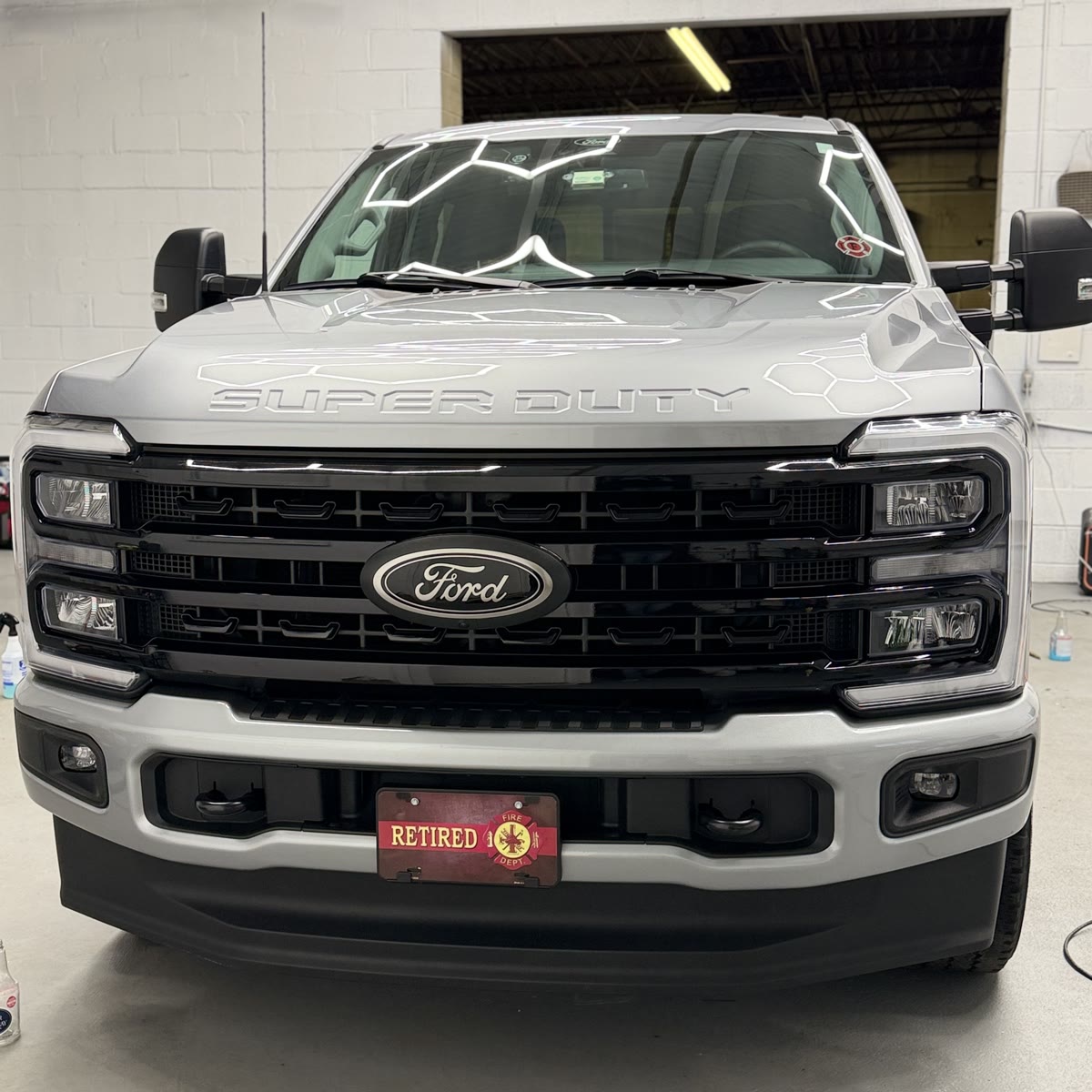Silver Ford F-250 Super Duty after ceramic coating, hexagon lights mirroring on windshield and hood
