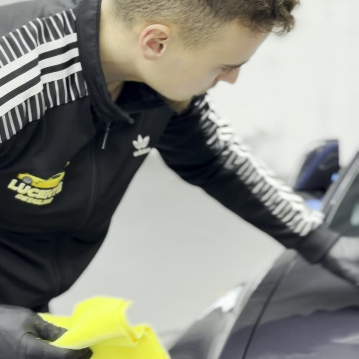 Levi Foss applying CCI ceramic coating to a vehicle hood — Lucente Detailing owner at work