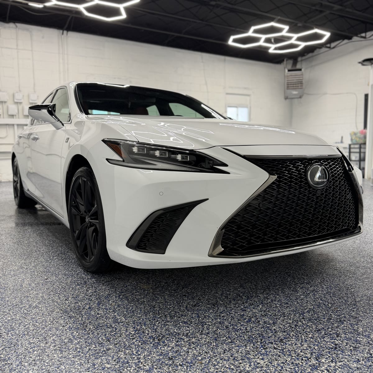 White Lexus F-Sport sedan after CCI ceramic coating, hexagon LED reflections on hood
